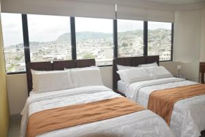 two beds in a room with a large window at Olan´s Hotel Group in Esmeraldas