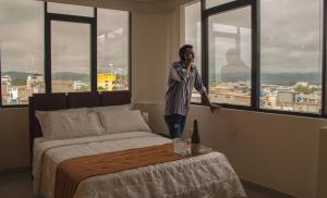 a man talking on a cell phone in a bedroom at Olan´s Hotel Group in Esmeraldas