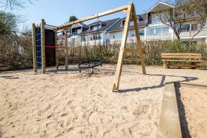 ein leerer Spielplatz mit einer Schaukel im Sand in der Unterkunft NeuKlosterhof App. 13 in Pelzerhaken