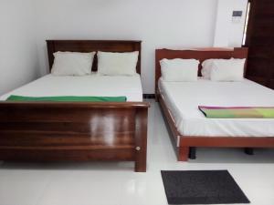 a bedroom with two beds and a rug at Priyanna Guest, Forest view in Polonnaruwa