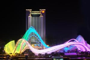 un edificio con una montaña rusa delante de él por la noche en Ramada Plaza Optics Valley Hotel Wuhan (Best of Ramada Worldwide) en Wuhan