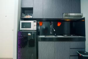 a small kitchen with a sink and a microwave at Minimalist Style 2BR Pakubuwono Terrace Apartment By Travelio in Jakarta