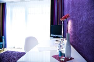 un escritorio con ordenador y un jarrón con una flor en Sky Design Motel, en Kriessern