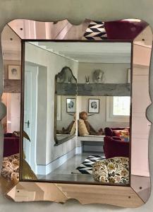 a mirror reflecting a living room with a man sitting on a couch at B&B Cà Bianca dell'Abbadessa in San Lazzaro di Savena