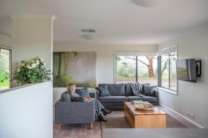 a woman sitting on a couch in a living room at McLaren Vale Getaways in McLaren Flat