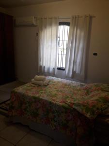 a bedroom with a bed with a quilt and a window at Hospedagem domiciliar in Guarujá