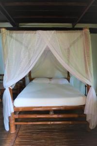 - un lit à baldaquin avec des draps et des oreillers blancs dans l'établissement VILLA MARMARINE BEACH RESORT & RESTAURANT, à Siquijor