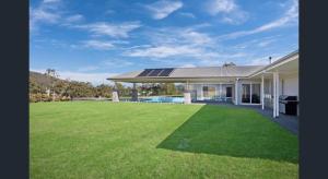 uma casa com um relvado com painéis solares em ON Keppies - BnB - Family Farm & Wedding Guest Accommodation Paterson NSW em Paterson