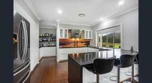 uma cozinha com um balcão e cadeiras em ON Keppies - BnB - Family Farm & Wedding Guest Accommodation Paterson NSW em Paterson