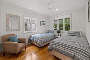 a bedroom with two beds and a chair and windows at The Keepers House in Toowoomba