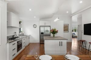 a kitchen with white cabinets and a table with flowers at The Keepers House in Toowoomba