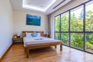 Schlafzimmer mit einem Bett und großen Fenstern in der Unterkunft Villas Owner in The Ocean Resort Da Nang in Đà Nẵng