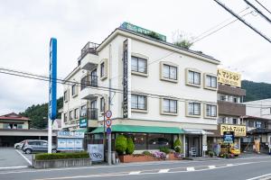 een groot wit gebouw op de hoek van een straat bij Kawaguchiko Station Inn in Fujikawaguchiko