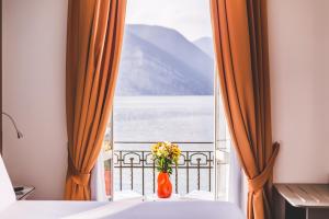 a vase of flowers sitting on a table in front of a window at Araba Fenice Hotel in Iseo
