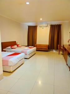 a hotel room with two beds and a desk at HOTEL & WISMA BINTANG JADAYAT in Bogor