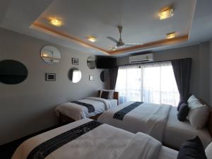 a hotel room with two beds and a window at The Besavana Phuket - SHA Extra Plus in Phuket Town