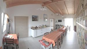 a dining room with tables and chairs and a kitchen at B&B S'Ena in Suni