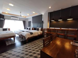 a hotel room with two beds and a table at The Besavana Phuket - SHA Extra Plus in Phuket Town