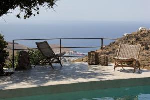 two chairs sitting on a patio next to a swimming pool at Villa Orso Blue I in Ioulis