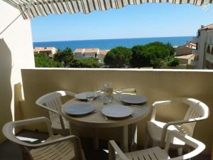 a table and chairs on a balcony with a view of the ocean at Coquet appartement in Fleury