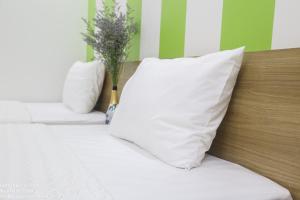 Una cama con almohadas blancas y un jarrón con flores. en Hùng Vương Hotel Hạ Long, en Ha Long