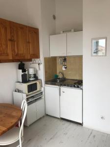 eine kleine Küche mit weißen Schränken und einem Tisch in der Unterkunft Coquet appartement in Fleury