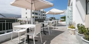 eine Terrasse mit Tischen und Sonnenschirmen auf einem Balkon in der Unterkunft Zzzone Boutique Hostel in Hermanus