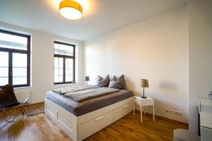 a white bedroom with a bed and two windows at ***Stylische Wohnung direkt am Hauptbahnhof*** in Leipzig