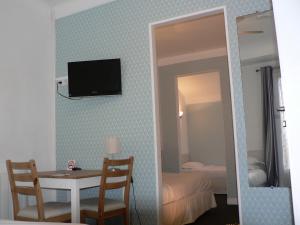um quarto com uma mesa e uma televisão na parede em Hôtel Les Alizés em Biarritz