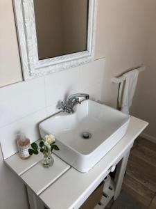 un lavabo blanc dans une salle de bain avec un miroir dans l'établissement Kandelaars Cottage, à Oudtshoorn
