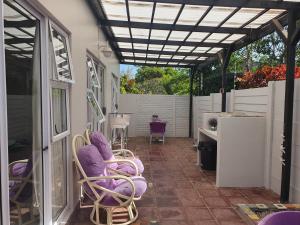 un patio con sillas moradas y pérgola en Nahoon Bed & Breakfast, en East London