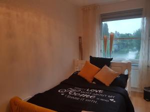 een slaapkamer met een bed met een raam en een sprei die vrolijke liefde leest bij Little Amsterdam in Uithoorn