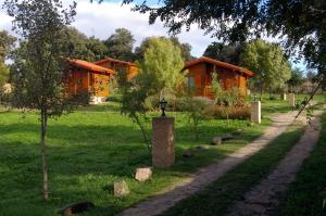 un chemin menant à deux maisons en bois dans un champ dans l'établissement Cabañas del Cortino, à Monleras