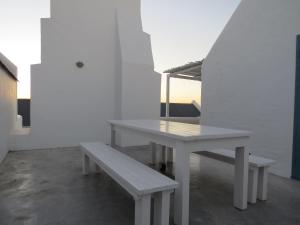 a white table and bench in a white room at Oppidraai B in Paternoster