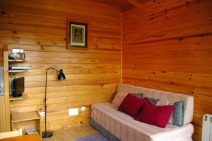 sala de estar con sofá en una pared de madera en Cabañas del Cortino, en Monleras