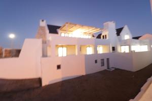 a white house with the lights on at Oppidraai B in Paternoster