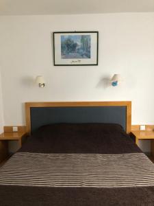 een slaapkamer met een bed met twee lampjes aan de muur bij Hôtel Au Petit Languedoc in Lourdes