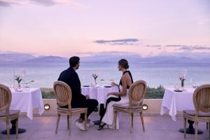 a man and woman sitting at a table in a restaurant at MarBella Nido Suite Hotel & Villas- Adults Only in Agios Ioannis Peristerion