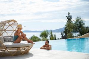 um homem e uma mulher sentados ao lado de uma piscina em Nido, Mar-Bella Collection em Agios Ioannis Peristerion
