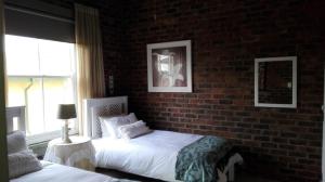 a bedroom with two beds and a brick wall at 712@Rest in Dullstroom