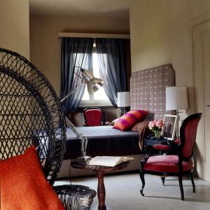 a bedroom with a bed and a chair and a window at Albergo l'Ostelliere - Villa Sparina Resort in Gavi