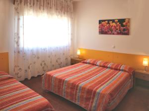 um quarto de hotel com duas camas e uma janela em Maria em Lignano Sabbiadoro