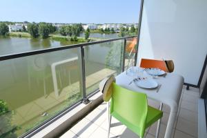 a balcony with a table and a view of a river at Appart-Hôtel Mer & Golf City Bordeaux - Bruges in Bruges
