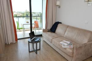 a living room with a couch and a laptop on a table at Appart-Hôtel Mer & Golf City Bordeaux - Bruges in Bruges