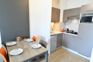 a dining room table with chairs and a kitchen at Appart-Hôtel Mer & Golf City Bordeaux - Bruges in Bruges