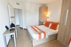 a bedroom with a bed and a desk with a laptop at Appart-Hôtel Mer & Golf City Bordeaux - Bruges in Bruges