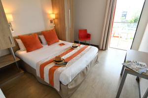 a hotel room with a bed with two hats on it at Appart-Hôtel Mer & Golf City Bordeaux - Bruges in Bruges