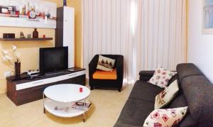 een woonkamer met een bank, een tv en een stoel bij Playa Mogan Golden Beach 1 by El Sirocco in Puerto de Mogán