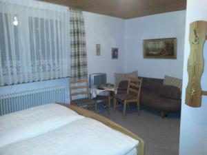 ein Schlafzimmer mit einem Bett, einem Sofa und einem Tisch in der Unterkunft Landgasthof Zur Mühle in Naila