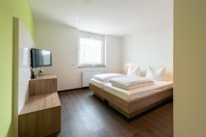 ein Schlafzimmer mit einem Bett und einem Flachbildfernseher in der Unterkunft a2 HOTELS Denkendorf - Airport & Messe in Denkendorf